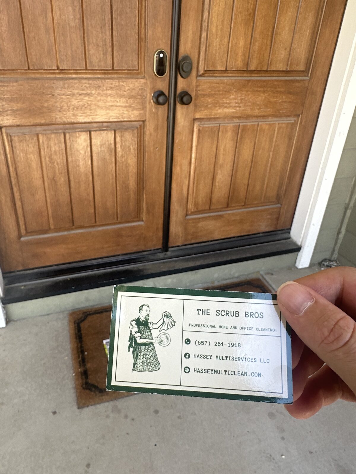 The Scrub Bros business card held at a customer's front door
