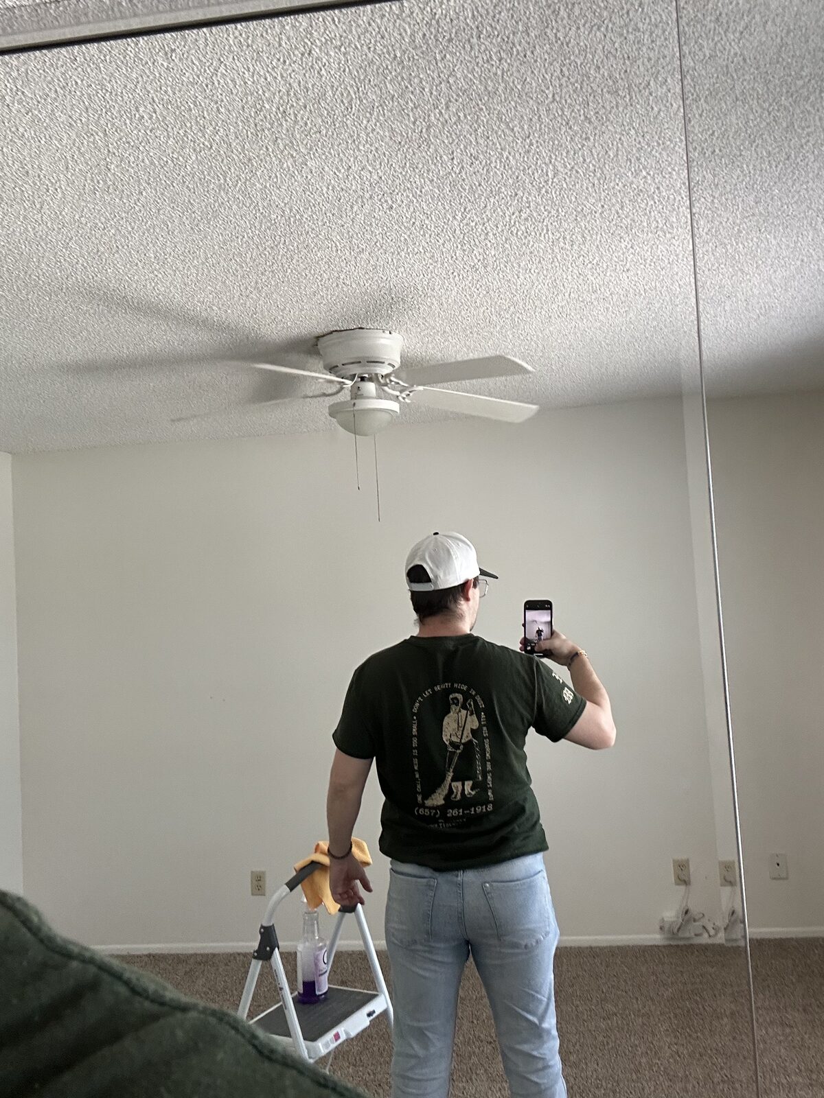 Scrub Bros team member dusting a ceiling fan from a step stool