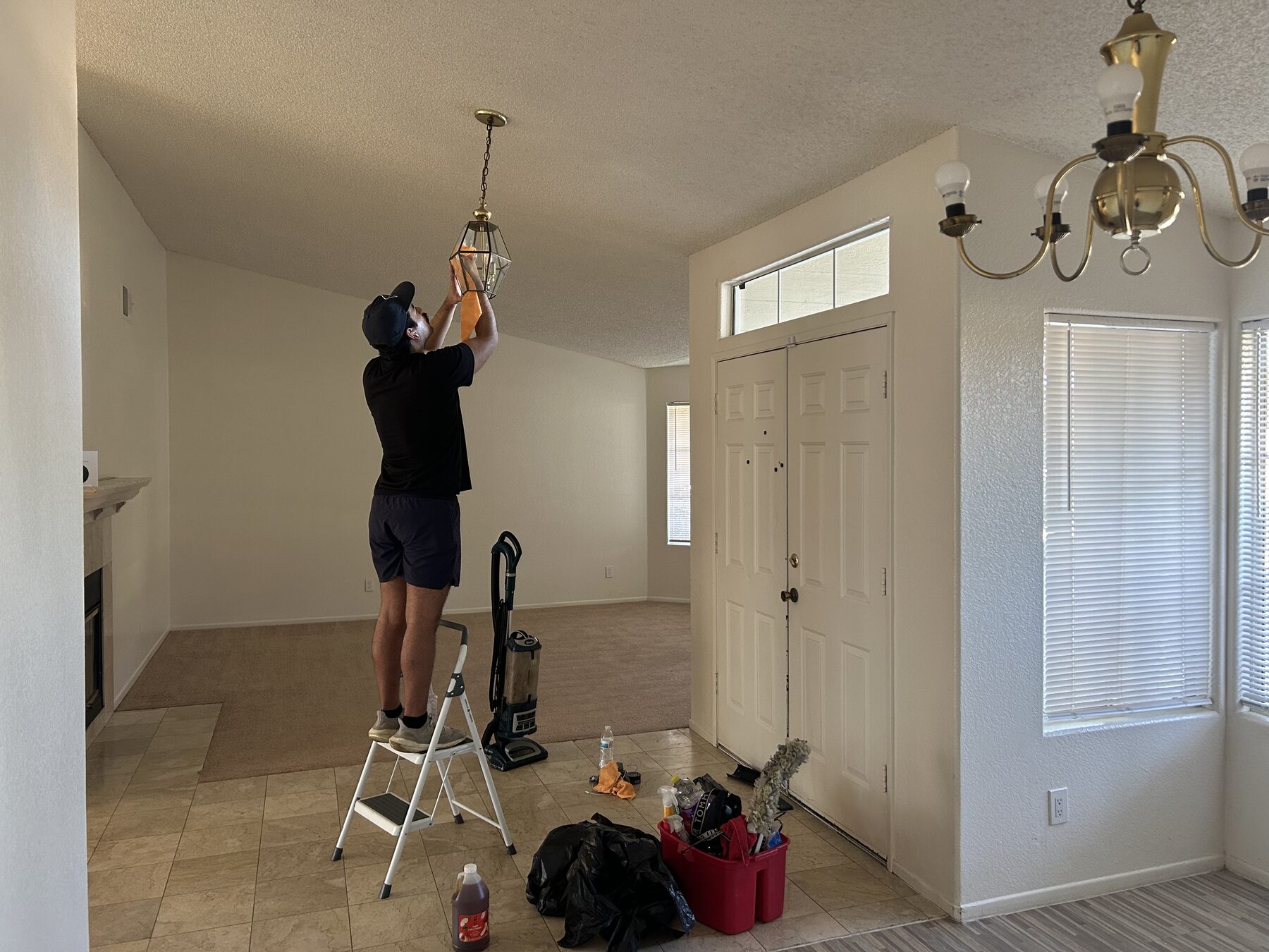 Scrub Bros team member cleaning a pendant light fixture during a move-out clean
