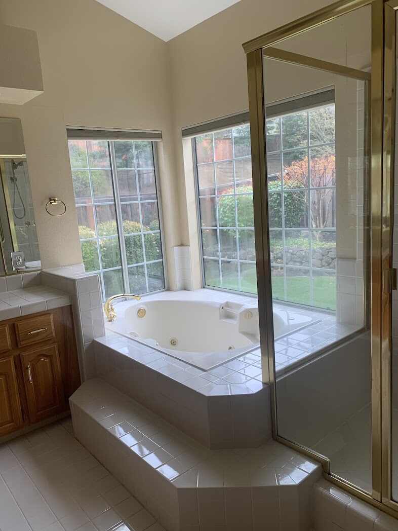 Primary bathroom with corner soaking tub and cleaned glass shower enclosure