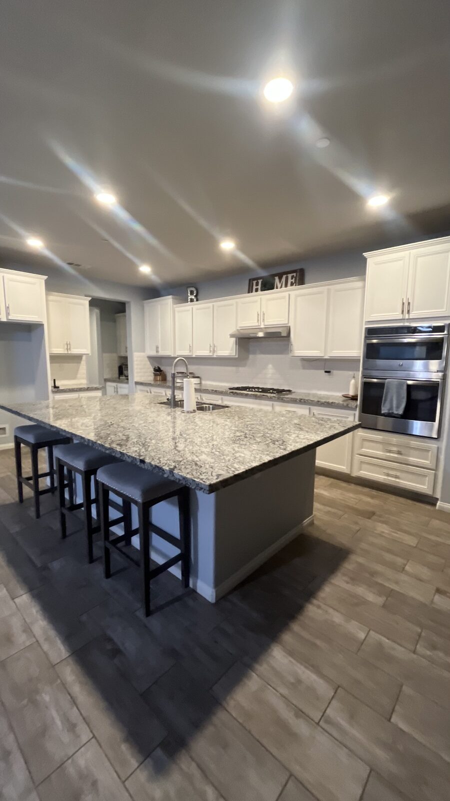 Large white kitchen with granite island and stainless double oven after a Scrub Bros clean