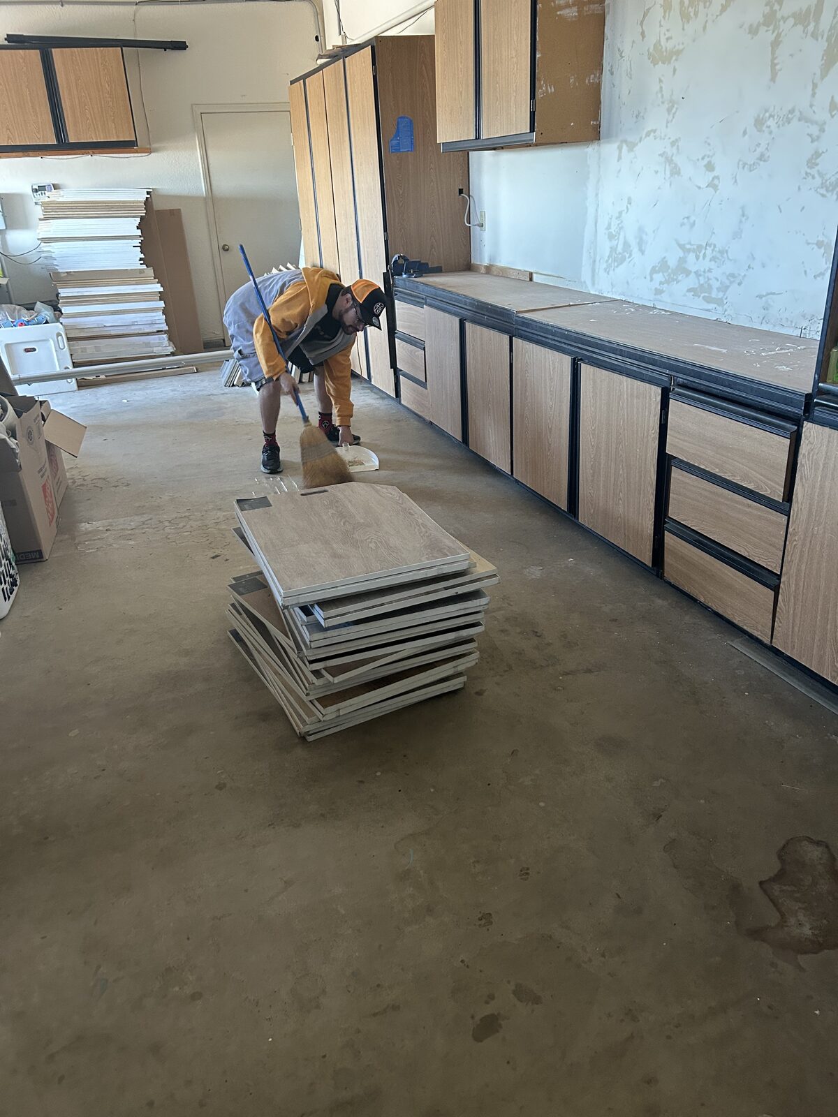 Scrub Bros team member sweeping construction dust from a garage workshop after a remodel