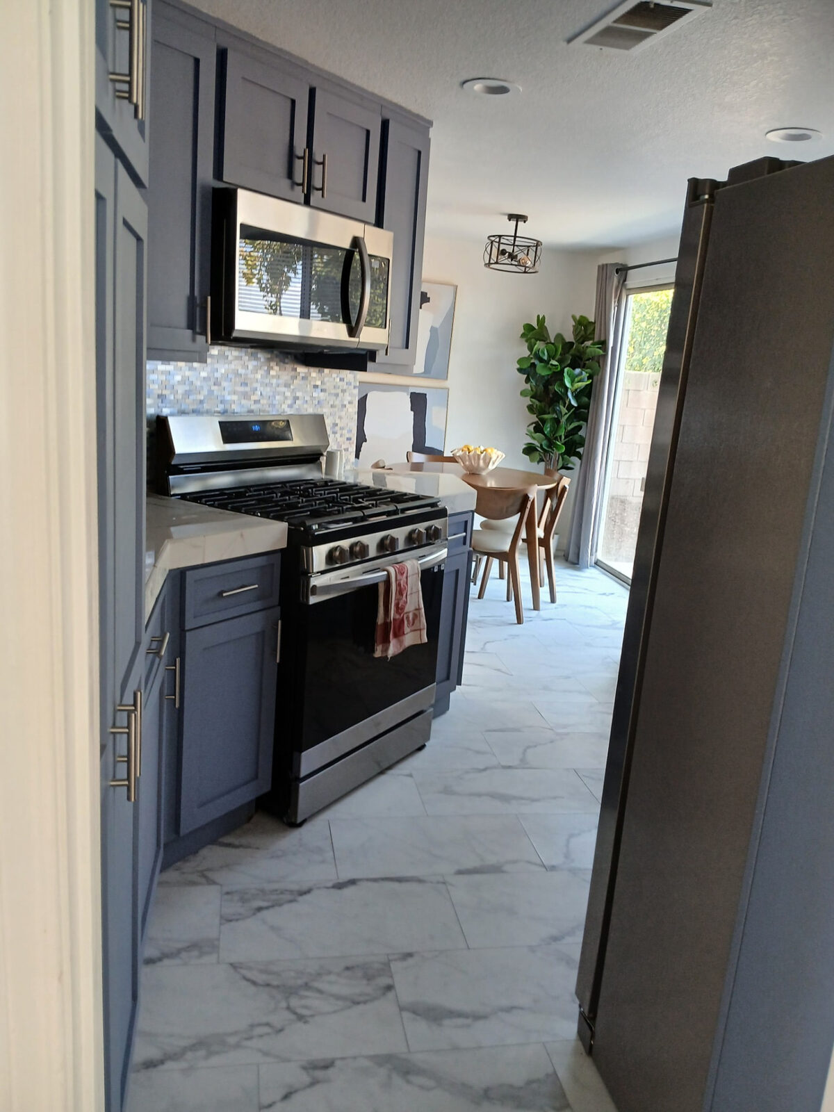 Kitchen with gray cabinetry and polished marble-look tile floor after cleaning